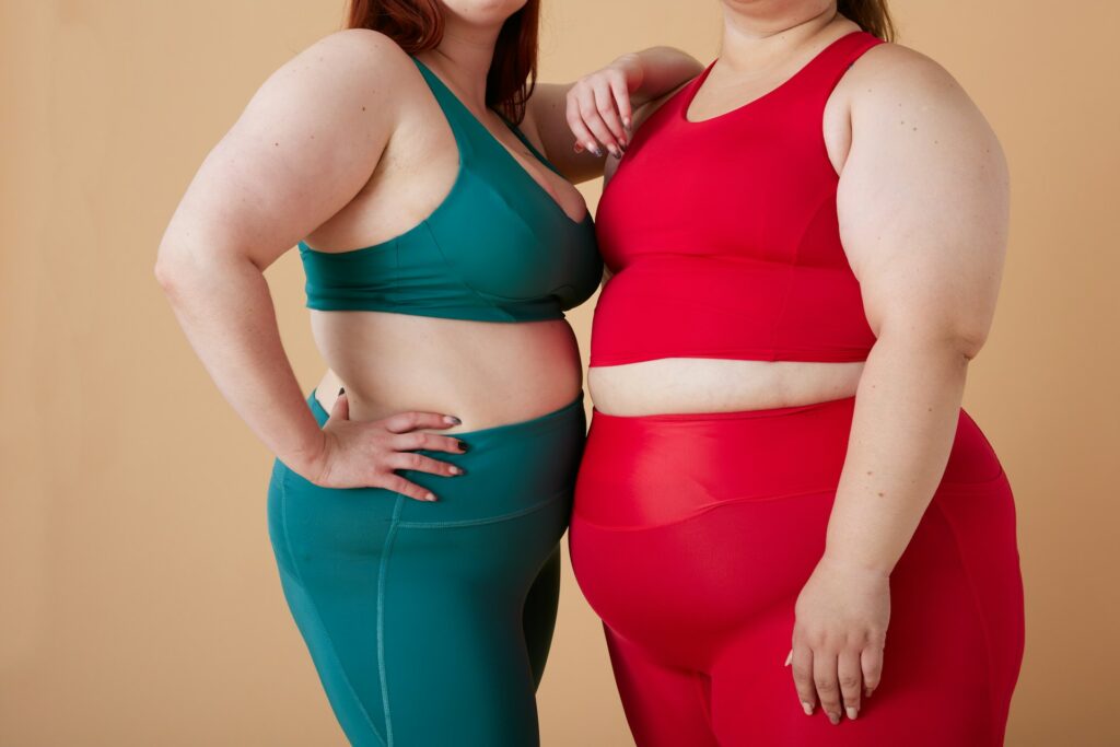 Two overweight women in workout clothing standing next to each other.